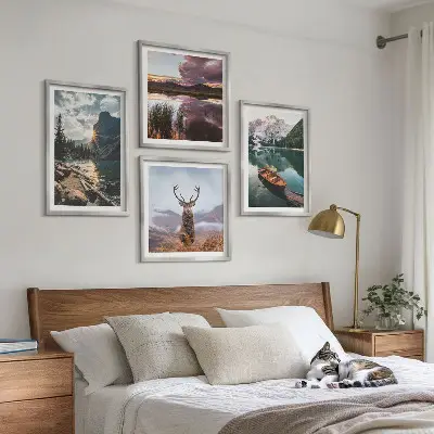 Billedvæg over sofa med motiv af bjerge, sø, båd, solnedgang og hjorte