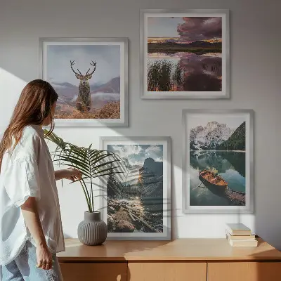 Billedvæg over sofa med motiv af bjerge, sø, båd, solnedgang og hjorte