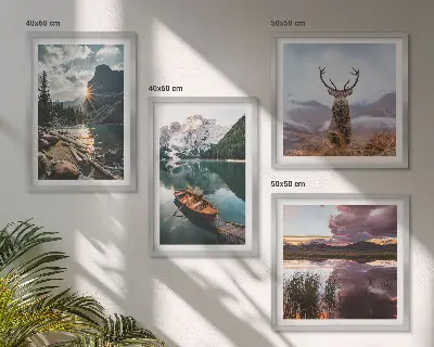 Billedvæg over sofa med motiv af bjerge, sø, båd, solnedgang og hjorte