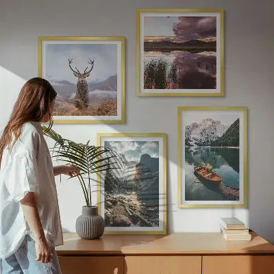 Billedvæg over sofa med motiv af bjerge, sø, båd, solnedgang og hjorte