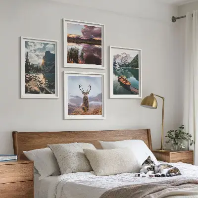 Billedvæg over sofa med motiv af bjerge, sø, båd, solnedgang og hjorte