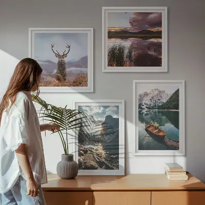 Billedvæg over sofa med motiv af bjerge, sø, båd, solnedgang og hjorte