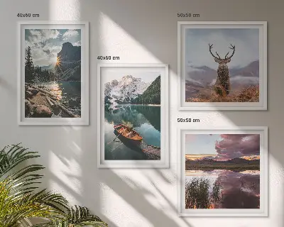 Billedvæg over sofa med motiv af bjerge, sø, båd, solnedgang og hjorte