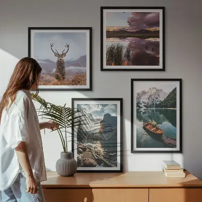 Billedvæg over sofa med motiv af bjerge, sø, båd, solnedgang og hjorte