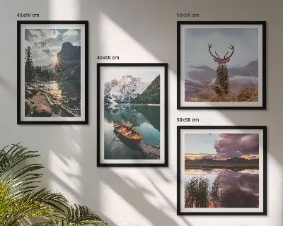 Billedvæg over sofa med motiv af bjerge, sø, båd, solnedgang og hjorte