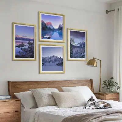 Billedvæg over sofa med bjerglandskaber, solnedgang og vand