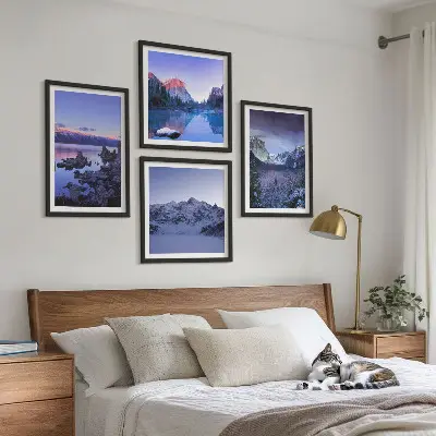 Billedvæg over sofa med bjerglandskaber, solnedgang og vand