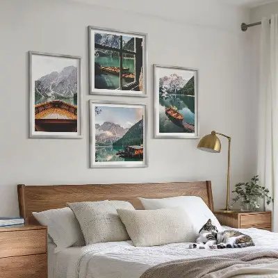 Billedvæg over sofa med motiv af sø, bjerge, både og sommerhus ved vinduet