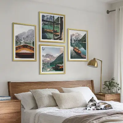 Billedvæg over sofa med motiv af sø, bjerge, både og sommerhus ved vinduet
