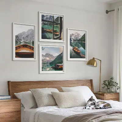 Billedvæg over sofa med motiv af sø, bjerge, både og sommerhus ved vinduet