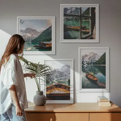 Billedvæg over sofa med motiv af sø, bjerge, både og sommerhus ved vinduet