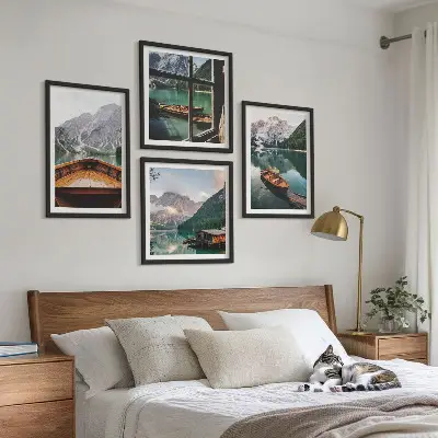 Billedvæg over sofa med motiv af sø, bjerge, både og sommerhus ved vinduet