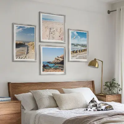 Billedvæg over sofa med motiv af strand, sand, bølger, himmel og fugle