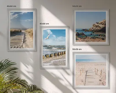 Billedvæg over sofa med motiv af strand, sand, bølger, himmel og fugle
