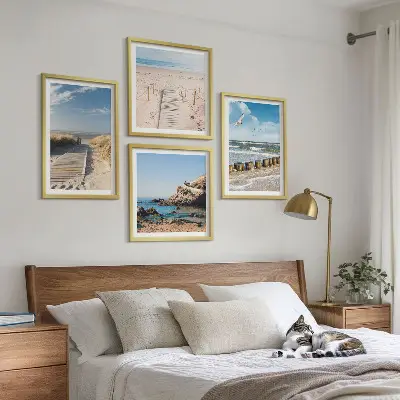 Billedvæg over sofa med motiv af strand, sand, bølger, himmel og fugle