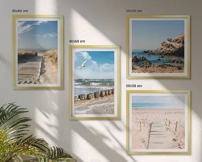 Billedvæg over sofa med motiv af strand, sand, bølger, himmel og fugle