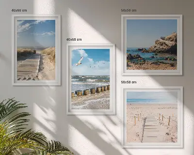 Billedvæg over sofa med motiv af strand, sand, bølger, himmel og fugle