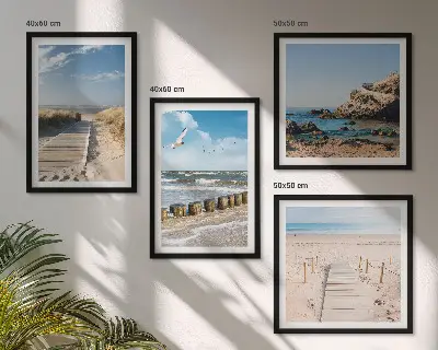 Billedvæg over sofa med motiv af strand, sand, bølger, himmel og fugle