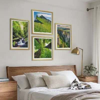 Billedvæg over sofa med motiv af grønne bjerge, vandfald og skov