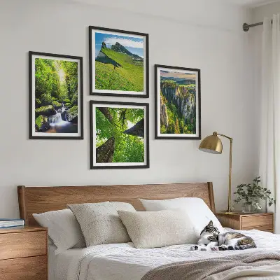 Billedvæg over sofa med motiv af grønne bjerge, vandfald og skov