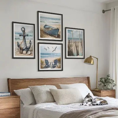 Billedvæg over sofa med motiv af anker, båd, årer og strand