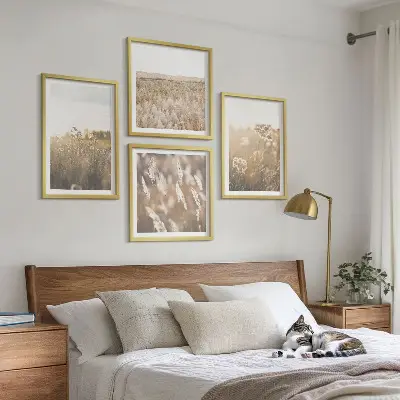 Billedvæg over sofa med motiv af landskabsgræs og blomster i varme nuancer