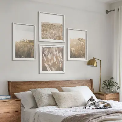 Billedvæg over sofa med motiv af landskabsgræs og blomster i varme nuancer