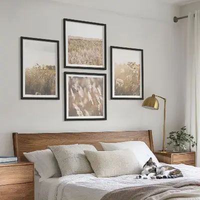 Billedvæg over sofa med motiv af landskabsgræs og blomster i varme nuancer