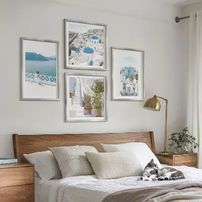 Billedvæg over sofa med motiv af hvide trapper, planter og hav