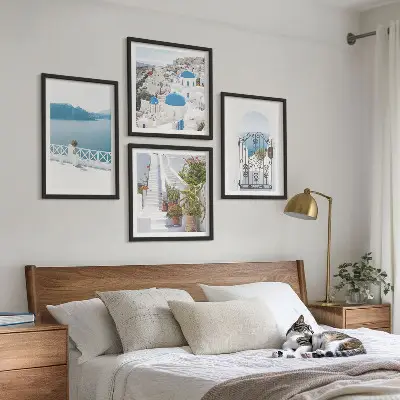 Billedvæg over sofa med motiv af hvide trapper, planter og hav